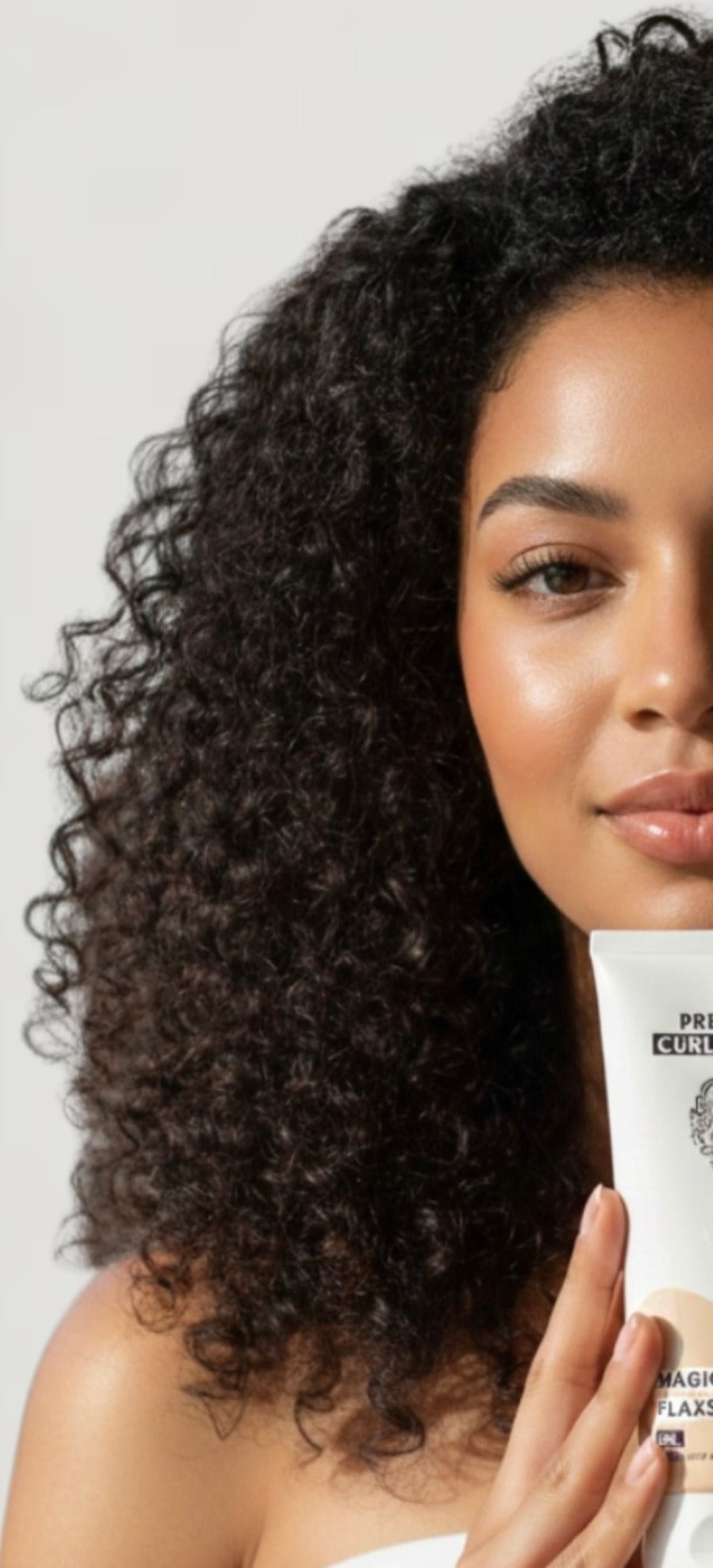 Woman with defined natural curls holding a Pretty Curly Girl USA Magical Flaxseed product